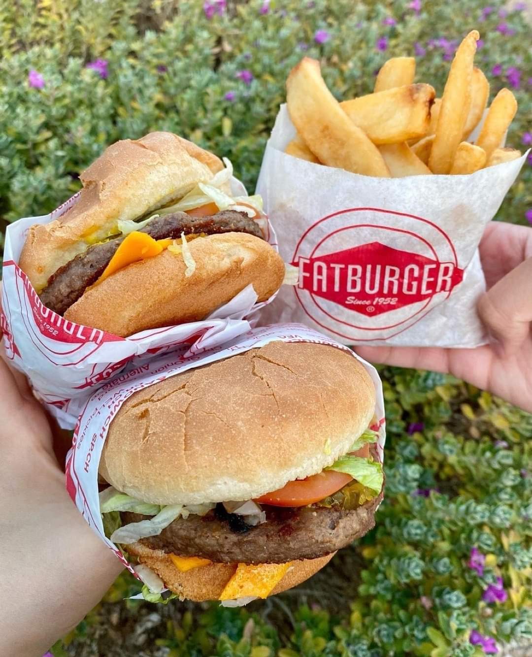 Person holding vegan burgers and fries from Fatburger