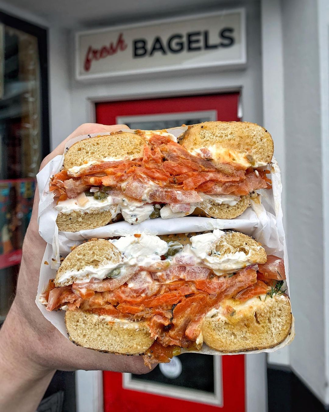 Person holding bagel sandwich from Ben & Esther's