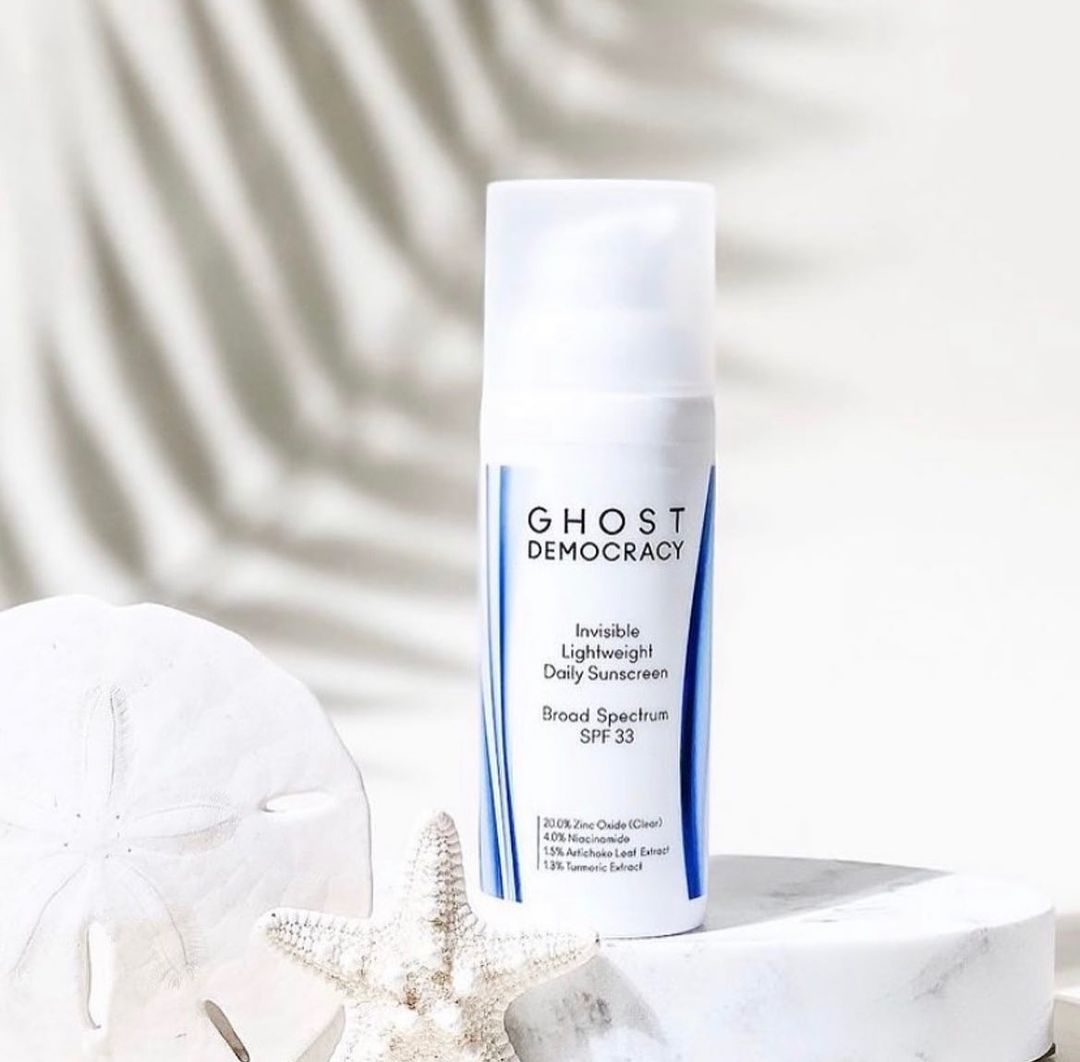 Ghost Democracy sunscreen on sand with seashells