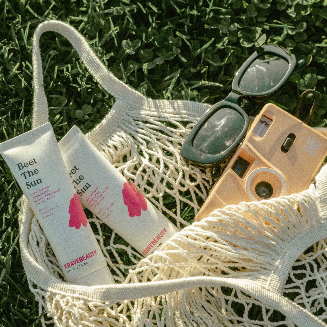 Krave Beauty sunscreen in purse with sunglasses and camera