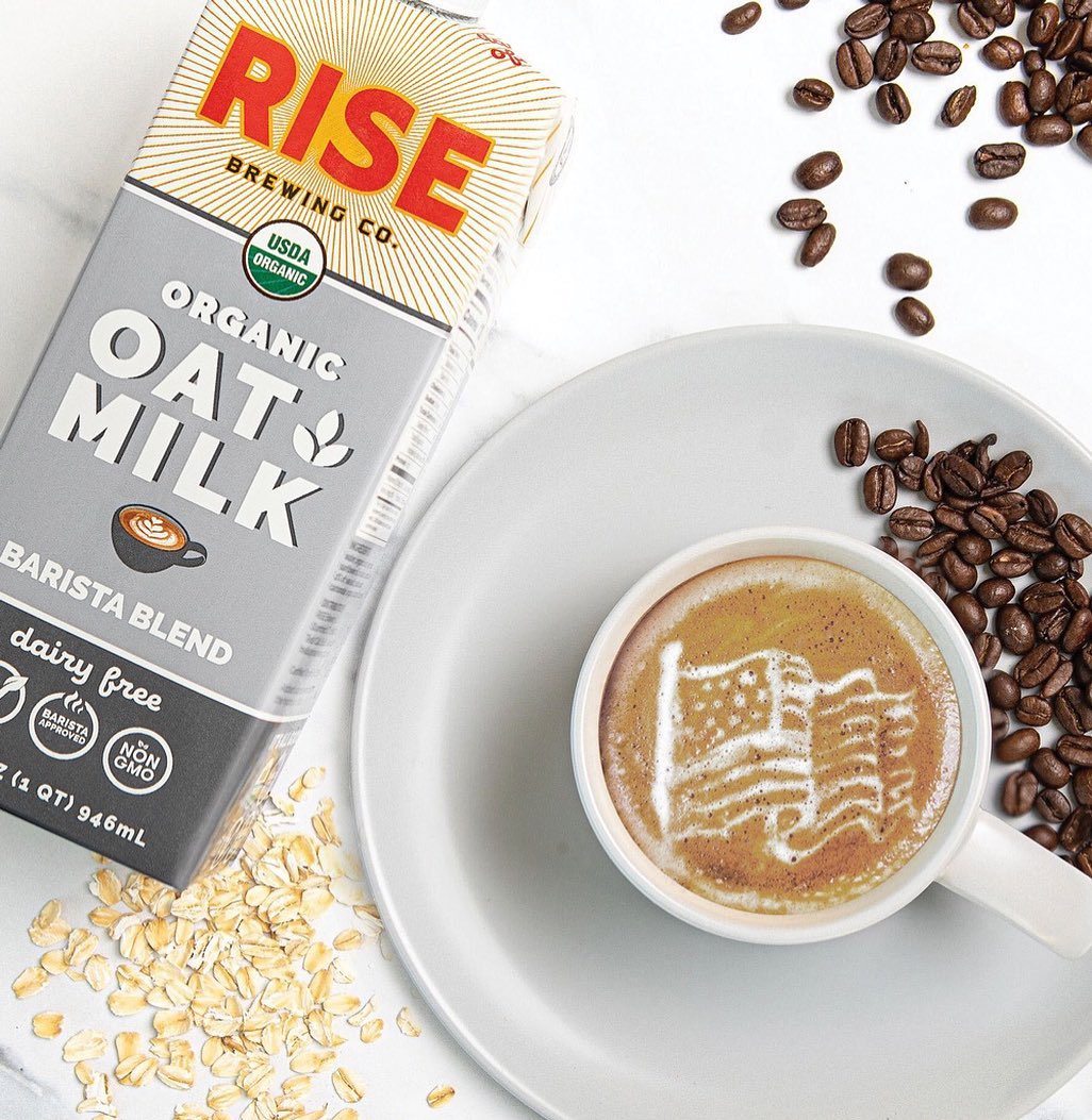 RISE Brewing Co. oat milk in drink surrounded by coffee beans