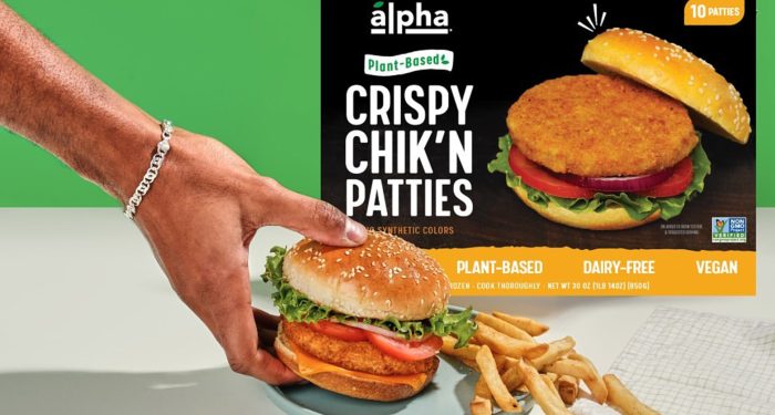 Person holding Alpha sandwich with packaging in the background
