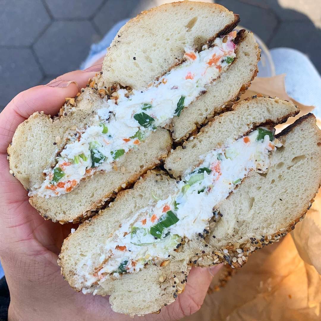 Person holding bagel sandwich from Brooklyn Bagel and Coffee Company