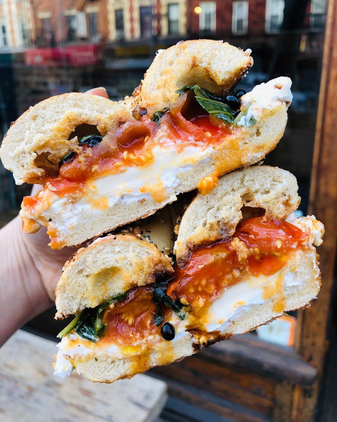 Person holding bagel sandwich from Familiars Vegan Coffee Shop