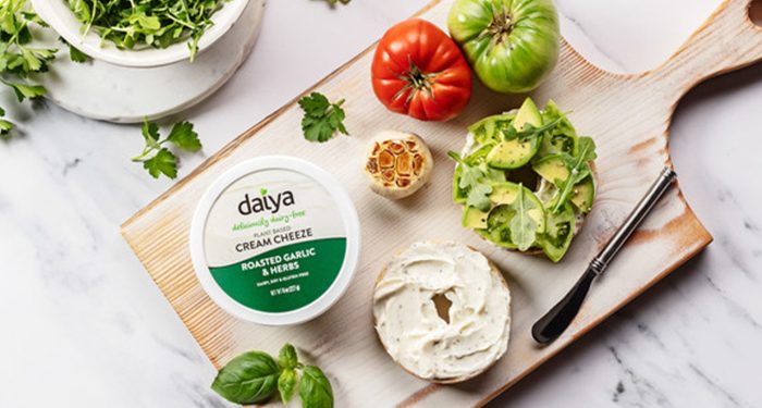 Daiya vegan cream cheese with bagels and vegetables on cutting board