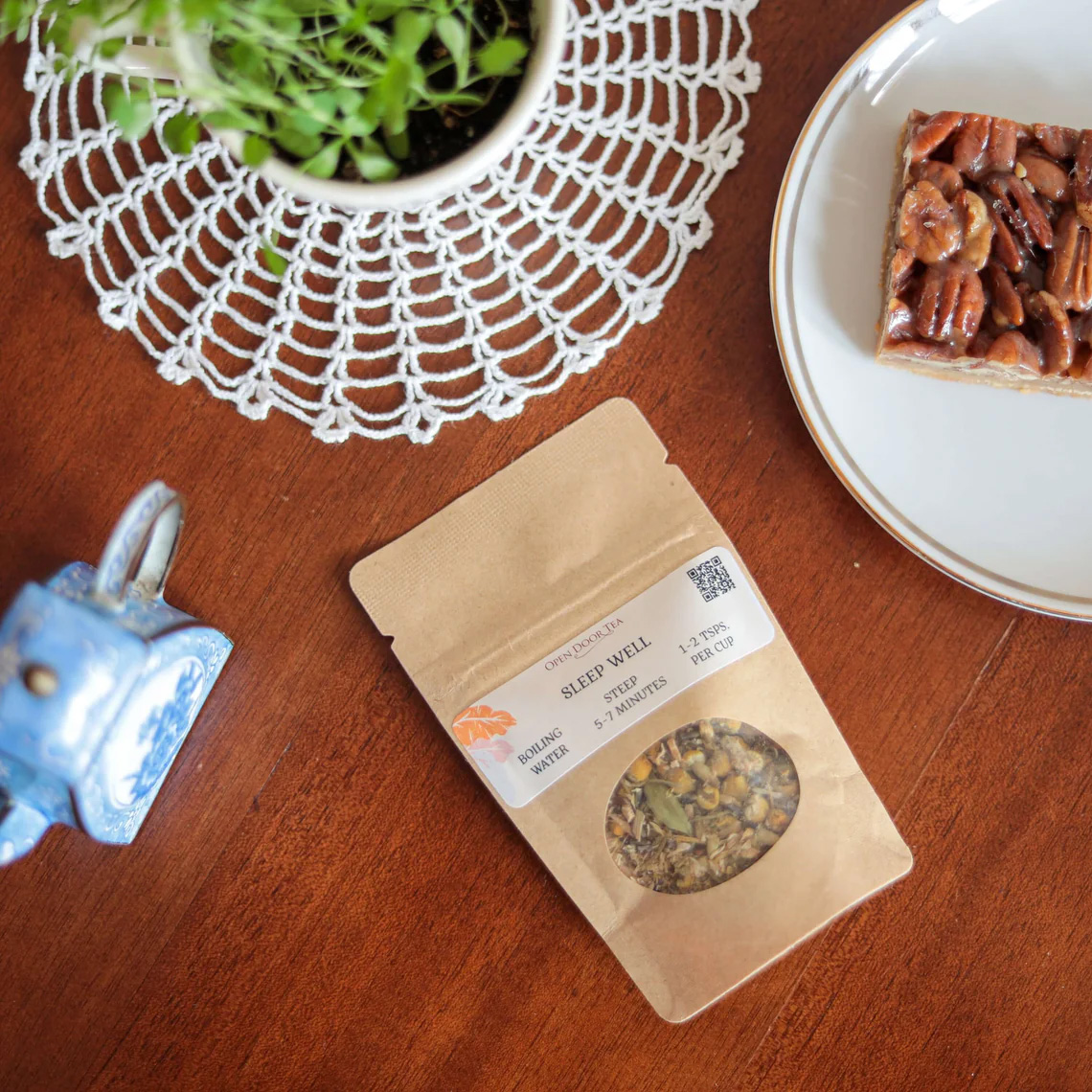 Open Door Tea packaging on table with plate of food and plant in background