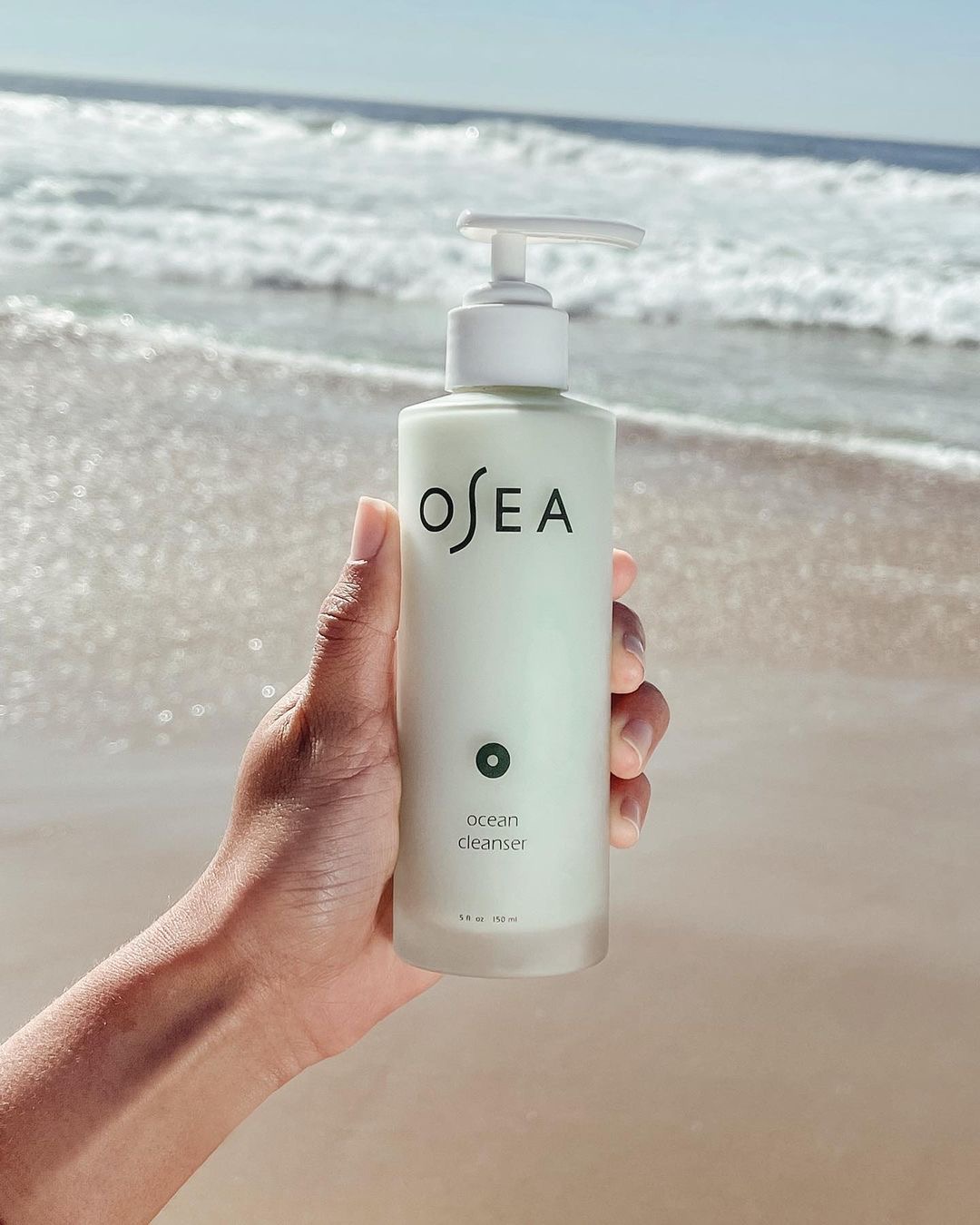 Person holding Osea product by the beach