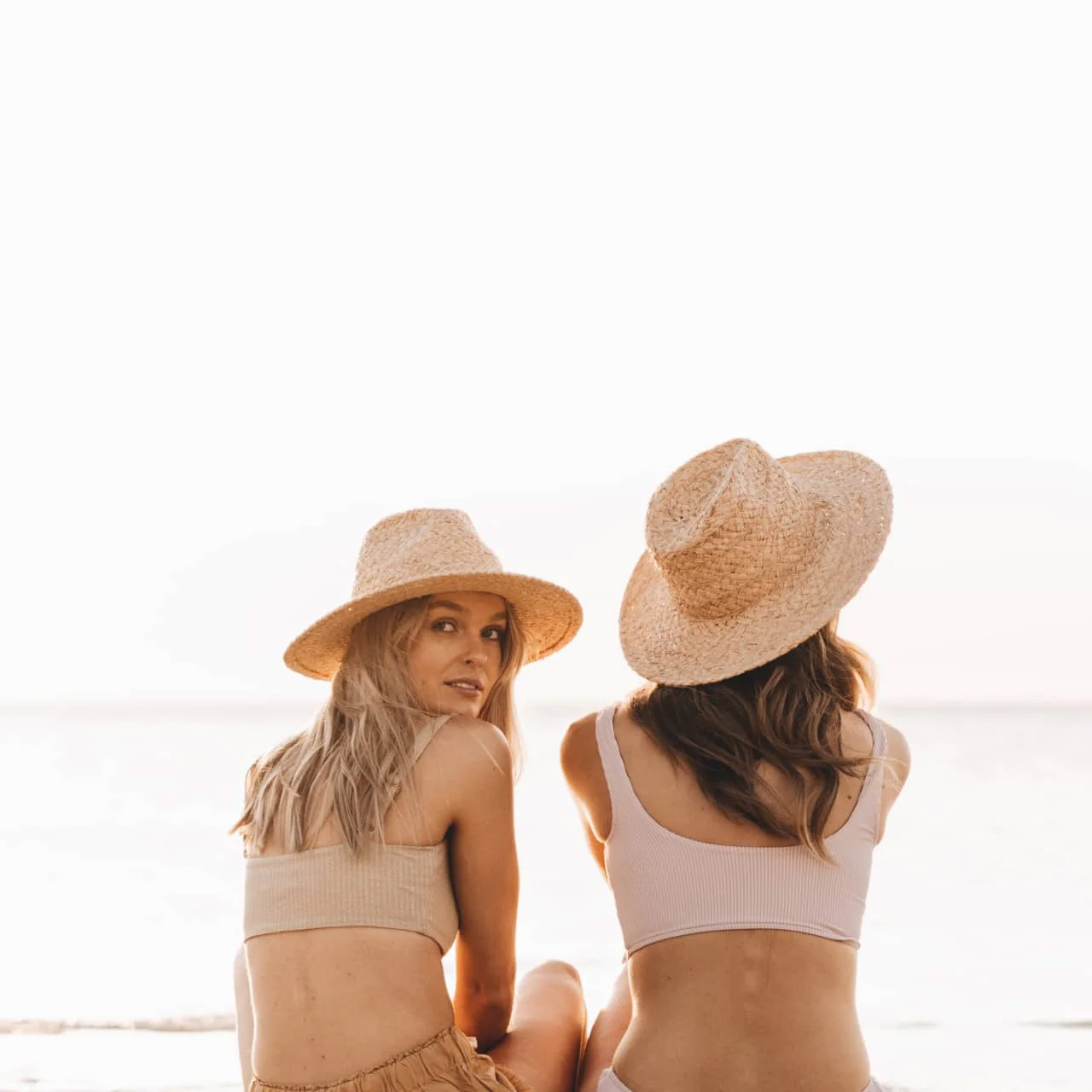 Two people on beach wearing Will + Bear hats