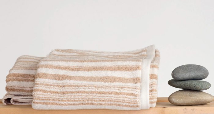 Rawganique towels on rack with rock