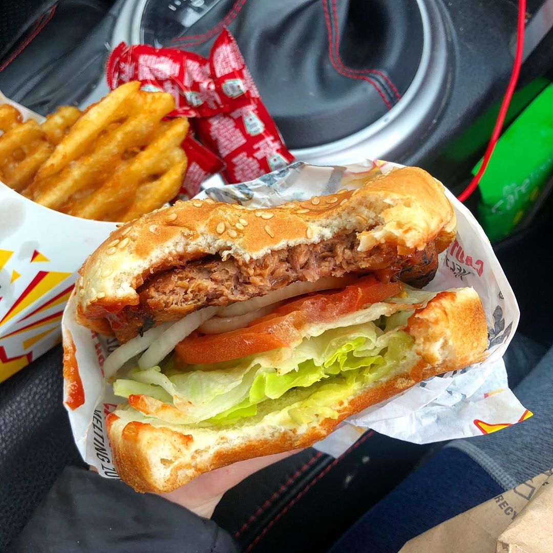 Person holding vegan burger and fries from Carls Jr.