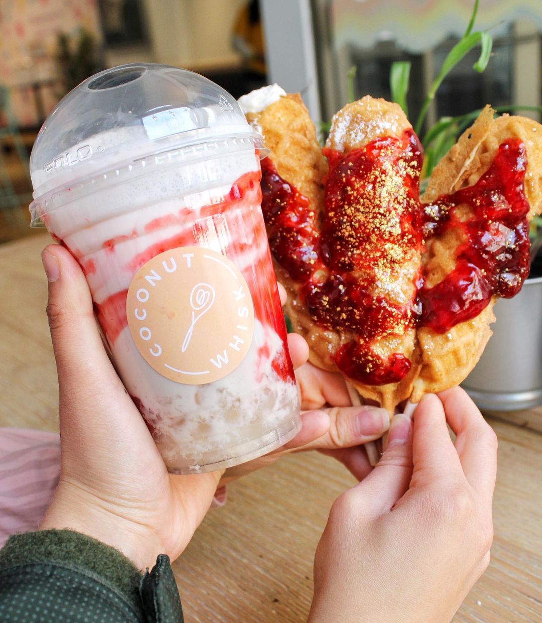 Person holding vegan milkshake and food from Coconut Whisk Café & Bubble Tea Shop