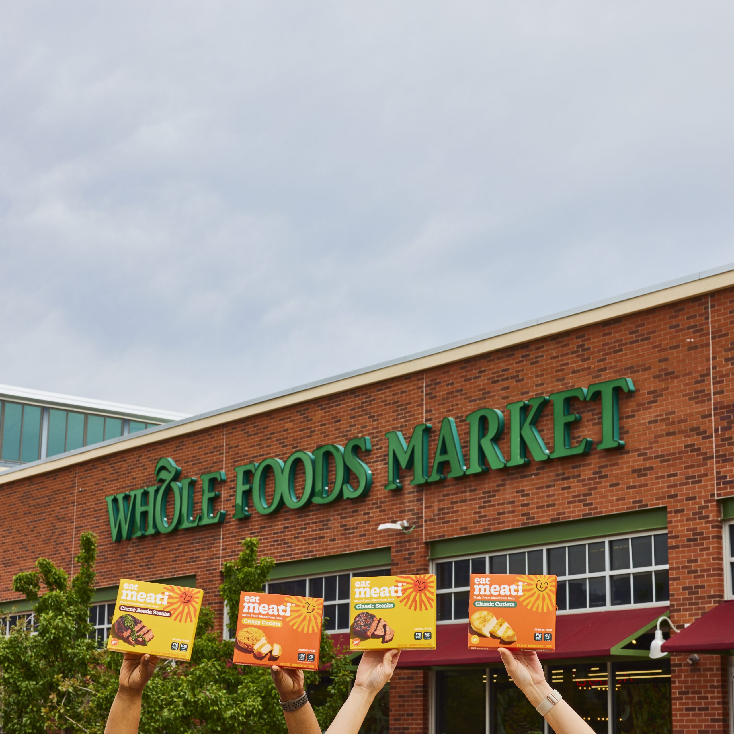 People holding up Meati products outside of Whole Foods