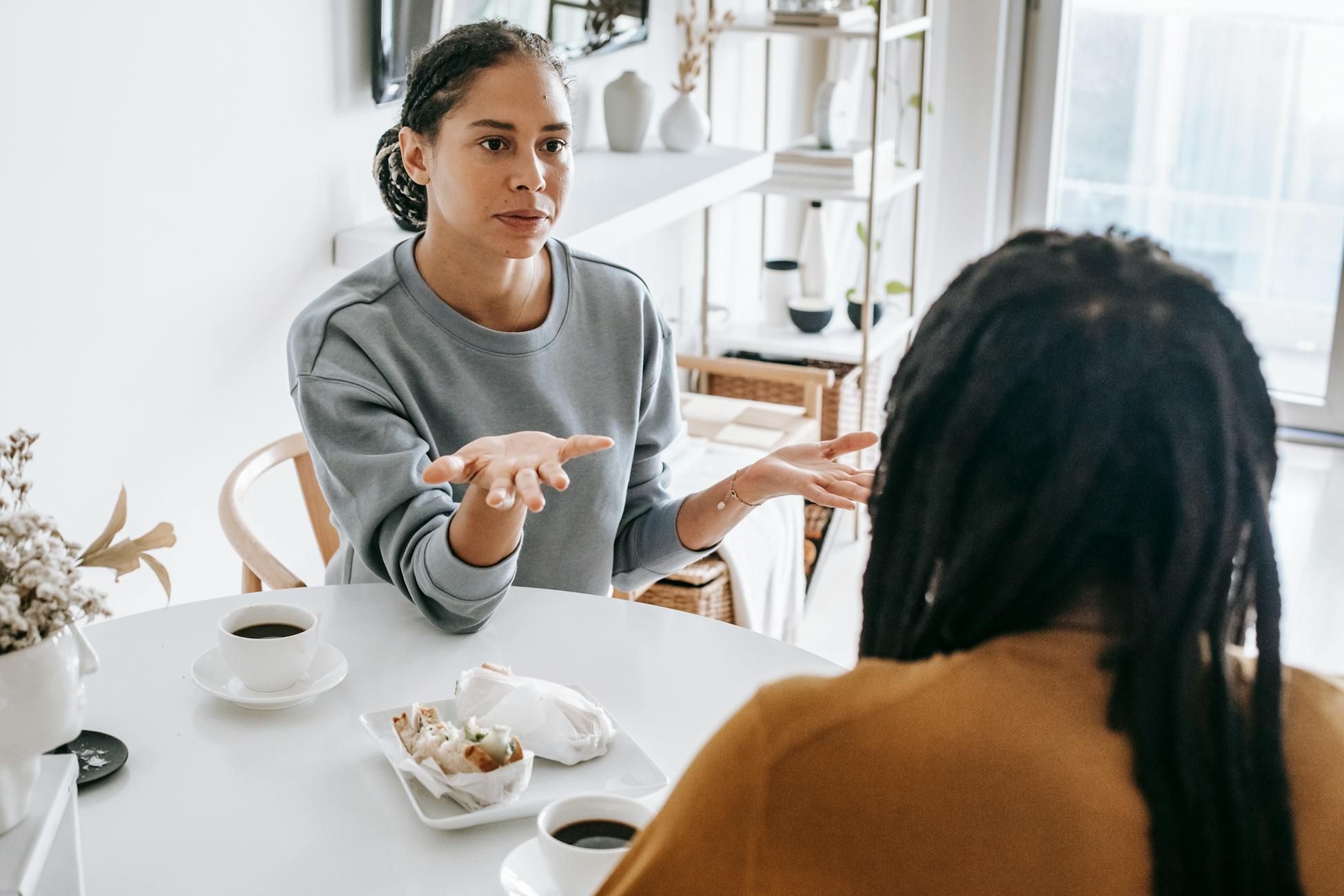 Young African American woman sitting at table and arguing with man in casual outfit in daylight