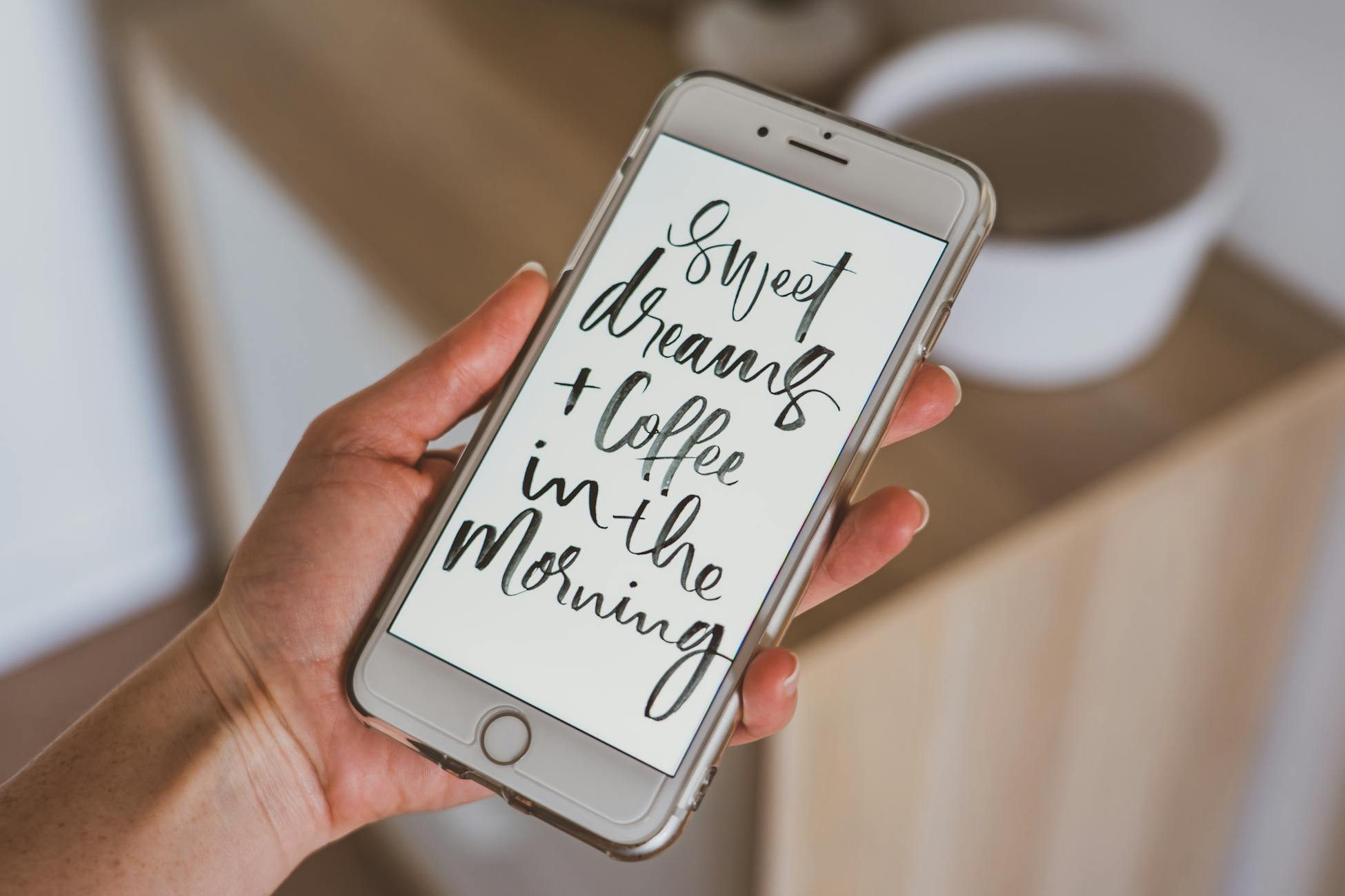 Hand holding smartphone displaying motivational quote with modern calligraphy font.