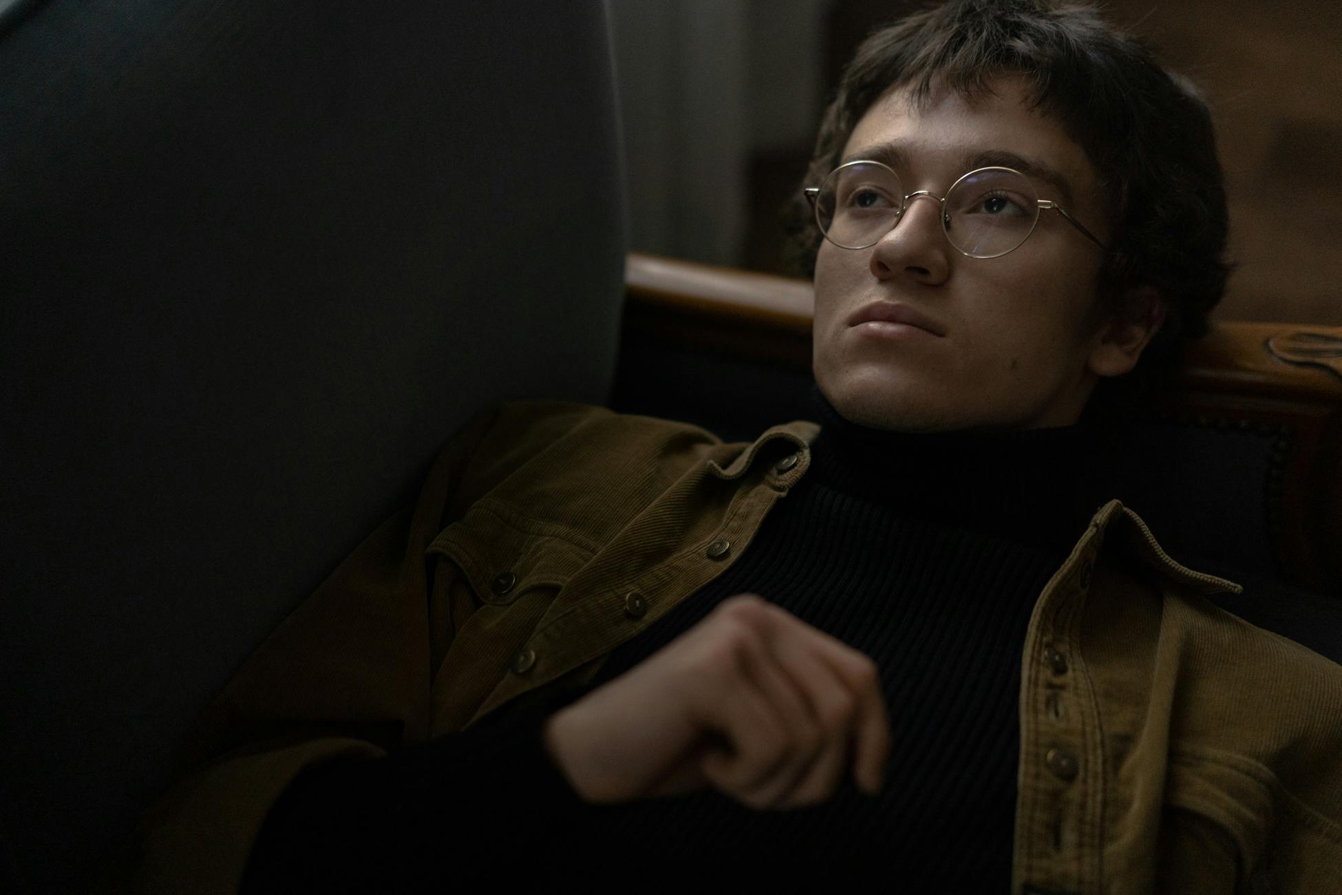 Pensive man wearing glasses resting indoors, conveying a contemplative mood.