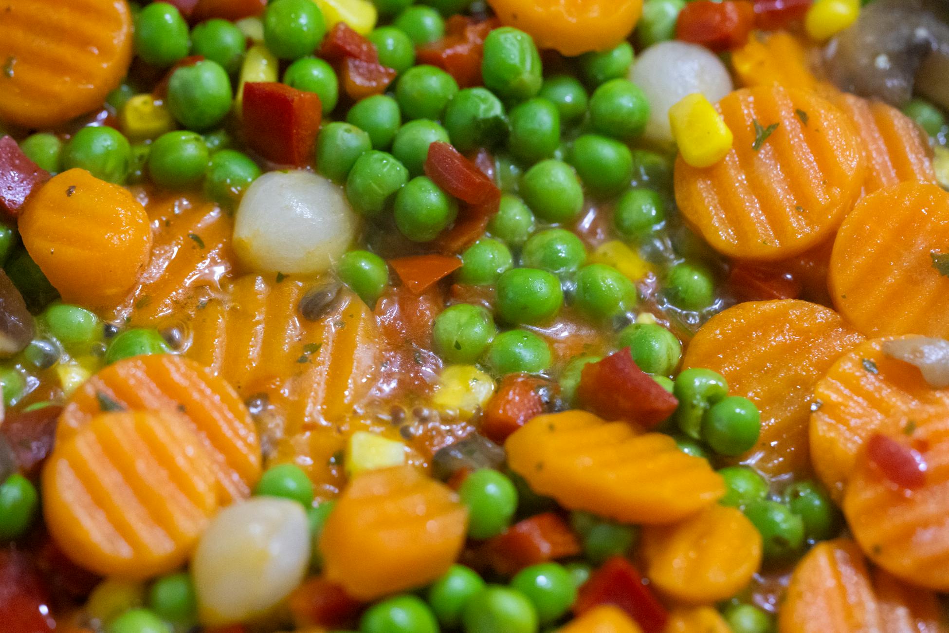 Vibrant close-up of mixed vegetables including carrots and peas in a stew.