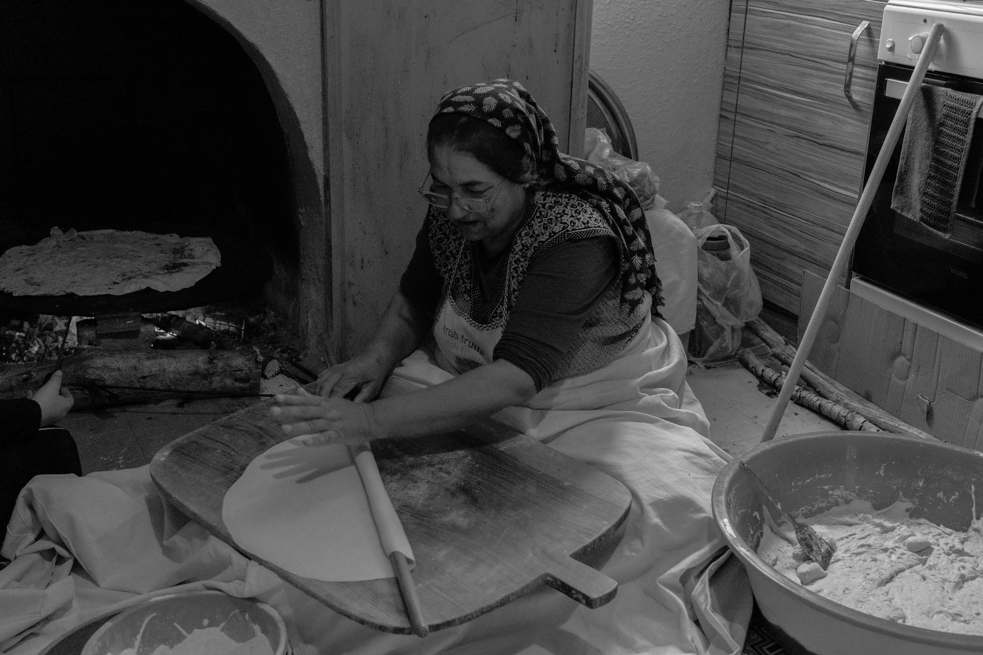 A woman prepares traditional bread in a rustic Turkish kitchen, showcasing cultural heritage.