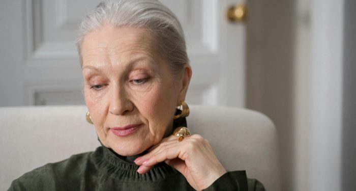 Elegant senior woman in thoughtful pose at home, reflecting grace.