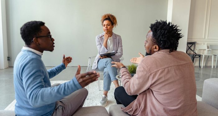 A therapy session featuring a diverse group discussing issues with a mental health professional.