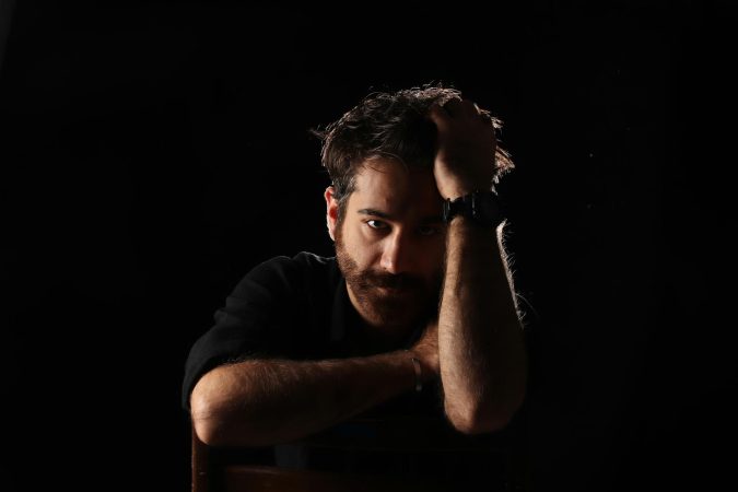 A contemplative man in a dark studio setting, captured in a dramatic and moody lighting.