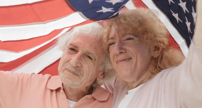 Happy senior couple holding an American flag, embracing love and togetherness.