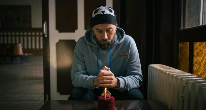A man reflects on his birthday with a cake at a cozy indoor setting in Istanbul.