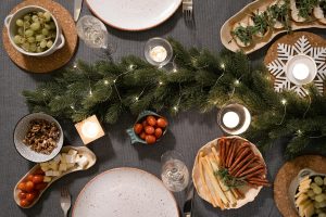 Aerial view of a holiday dinner table with festive decorations and assorted appetizers.
