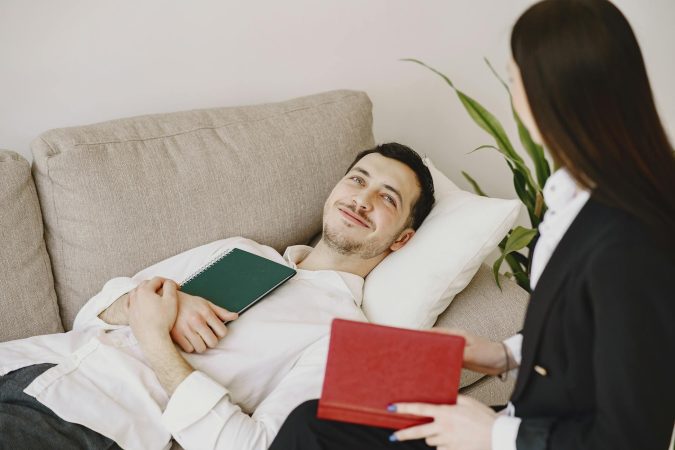 A relaxed patient lying on a couch during a therapy session with a professional therapist.
