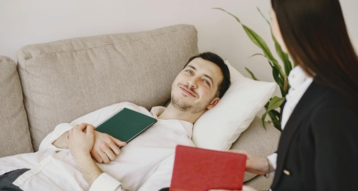 A relaxed patient lying on a couch during a therapy session with a professional therapist.