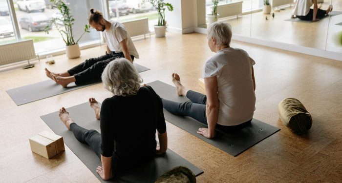 Adults participating in a relaxing yoga session in a serene studio environment.