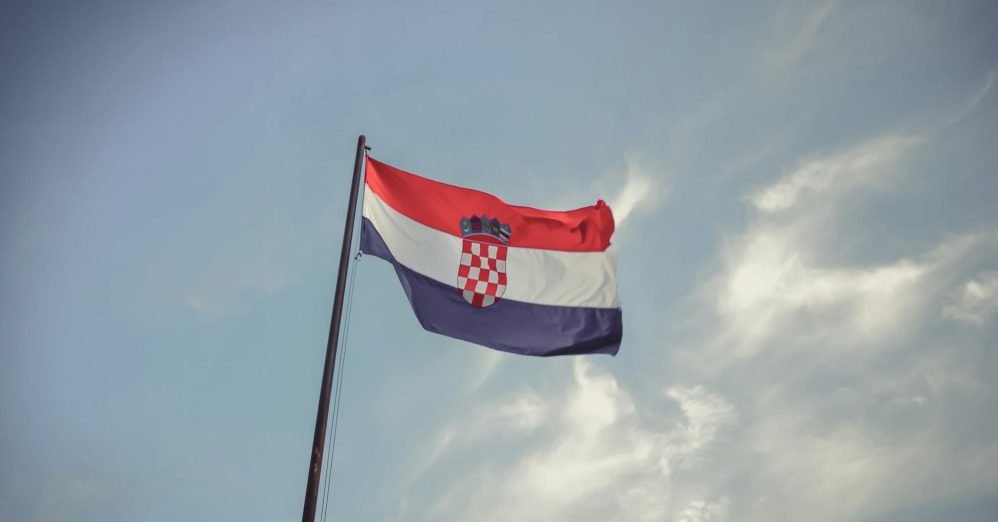 The Croatian flag blowing in the wind against a clear blue sky, symbolizing national pride.