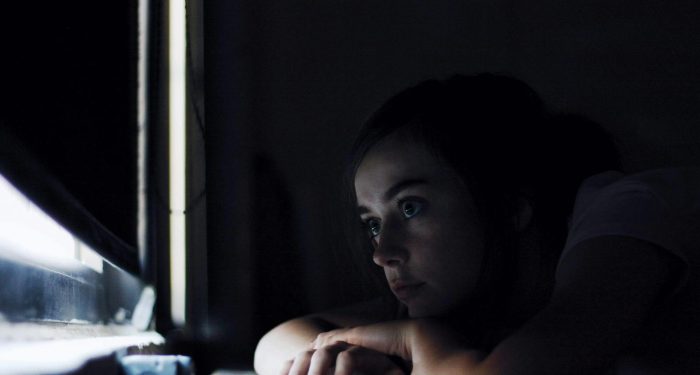 Woman gazing out a window, reflecting on loneliness and connection in her 40s