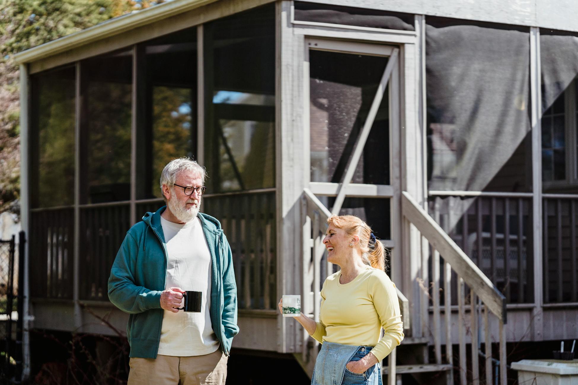 Senior couple relaxing with coffee on a sunny veranda, enjoying a peaceful day outdoors.