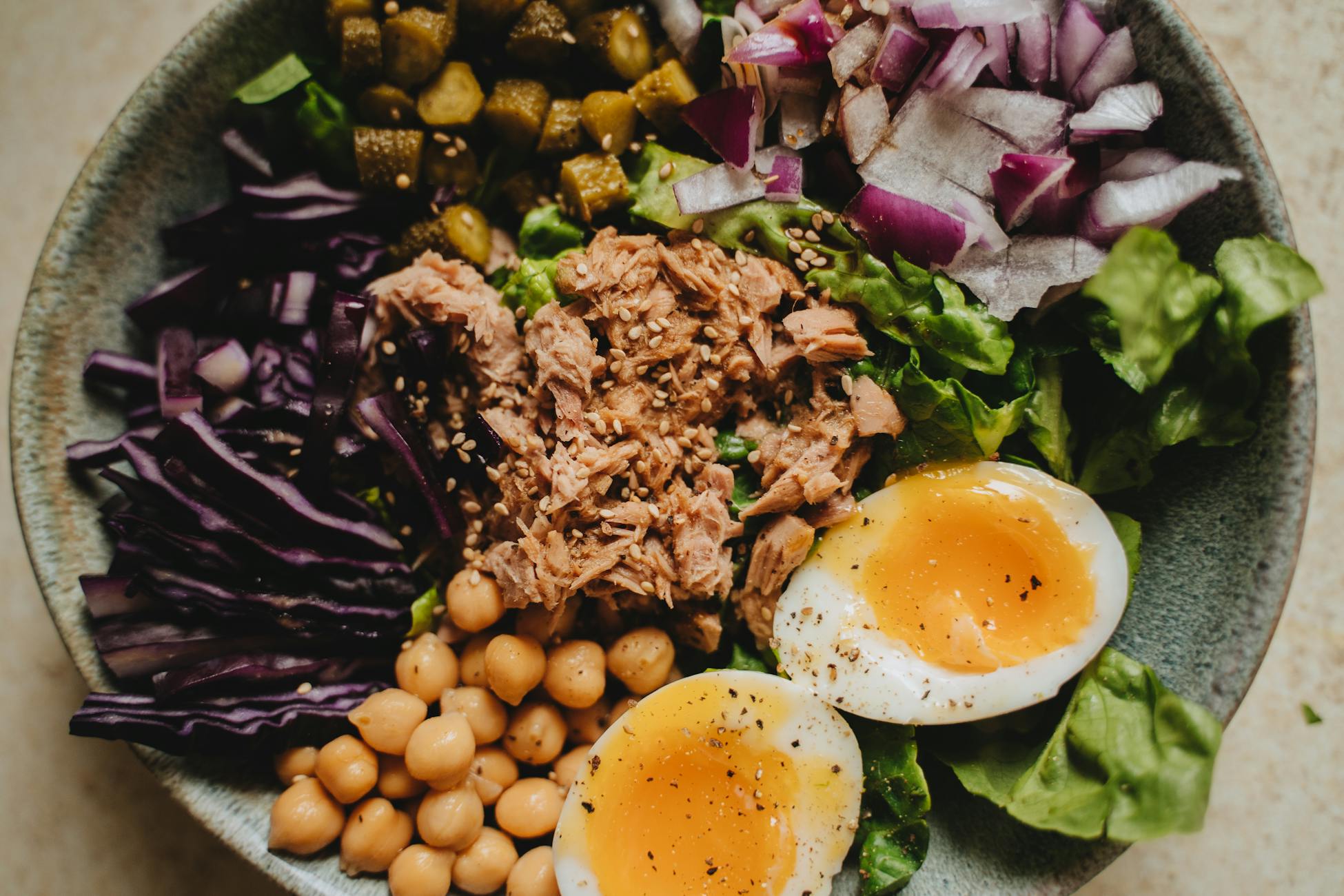 A nutritious Buddha bowl featuring tuna, chickpeas, vegetables, and poached eggs.