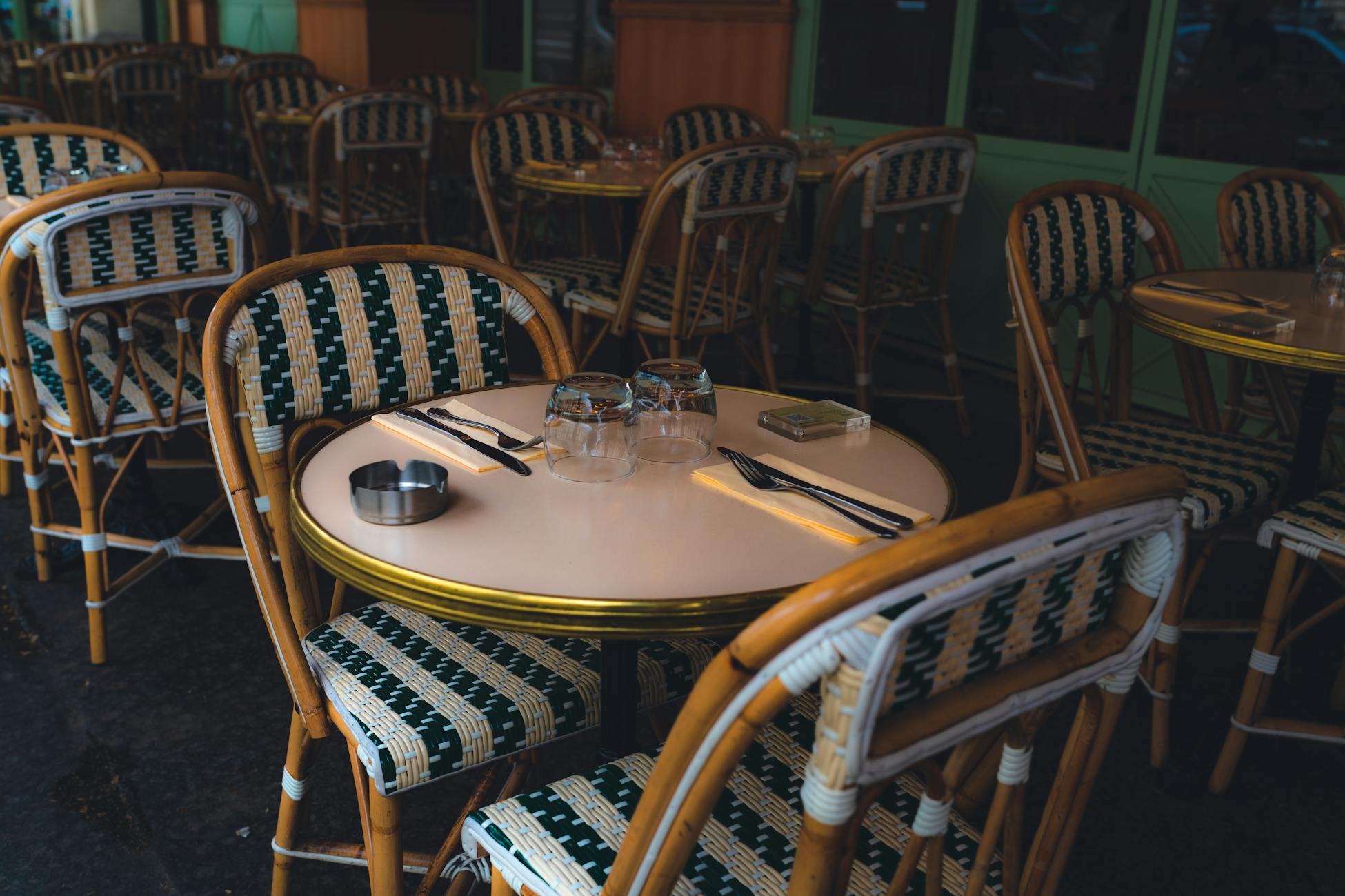 A charming outdoor restaurant setup with wicker chairs and dining tableware.