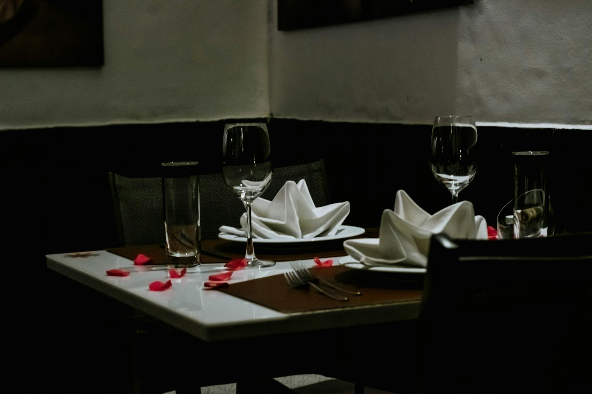 A romantically set dinner table with napkins and wineglasses, creating a luxurious ambiance indoors.