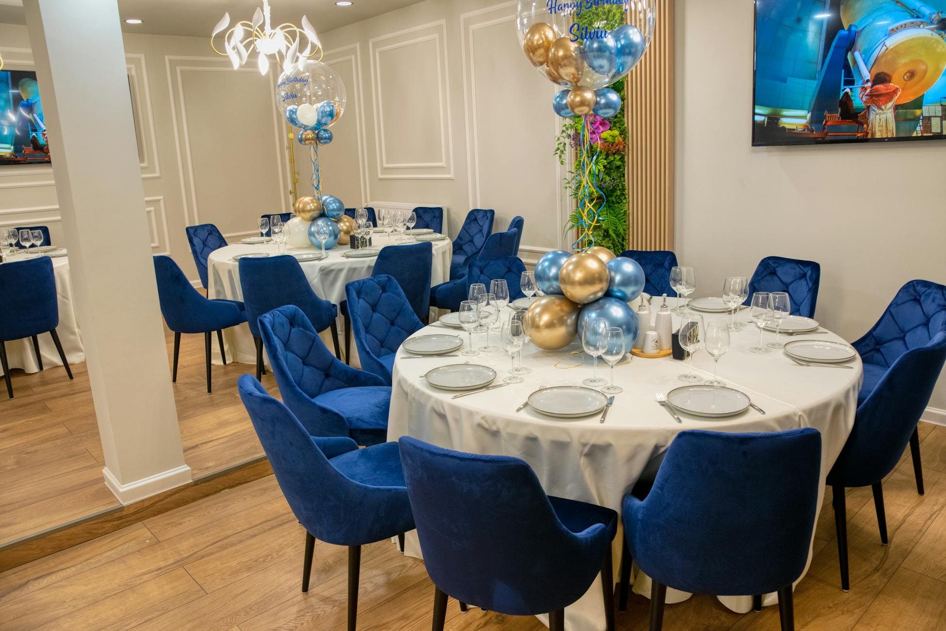 An elegantly decorated dining room with blue chairs and balloon centerpieces.