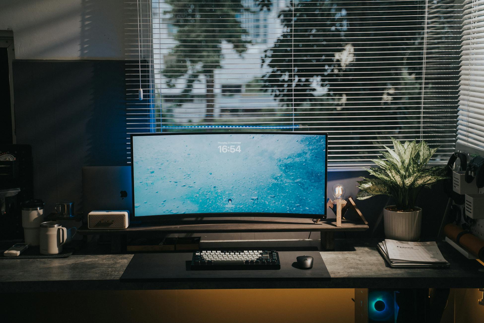 A stylish home office setup with a computer monitor, keyboard, mouse, and plant on a desk.