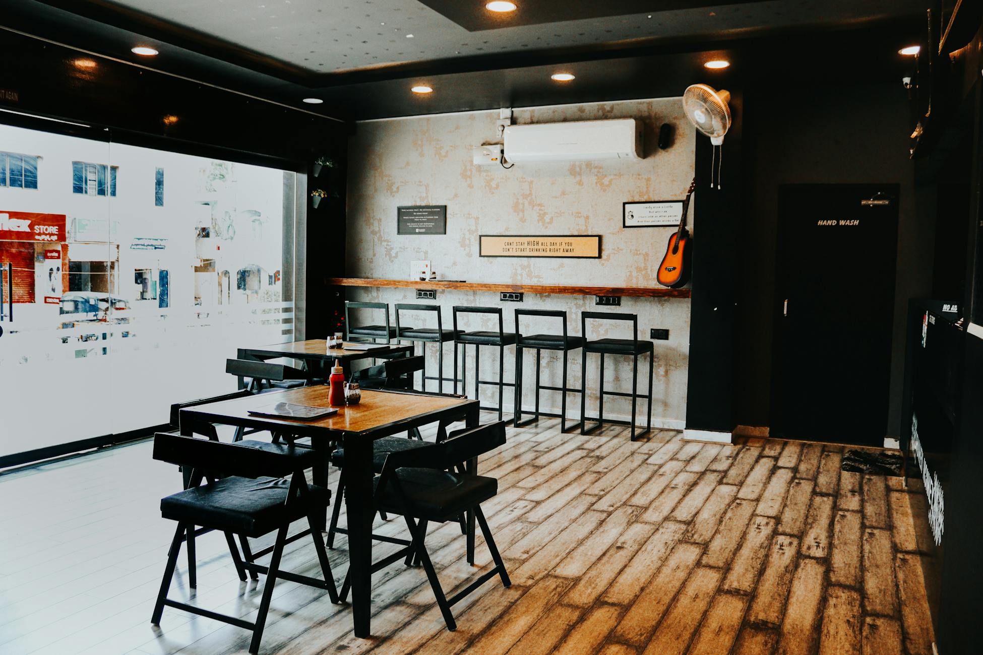 Industrial-themed café interior with wooden furniture and large windows in a cozy setting.
