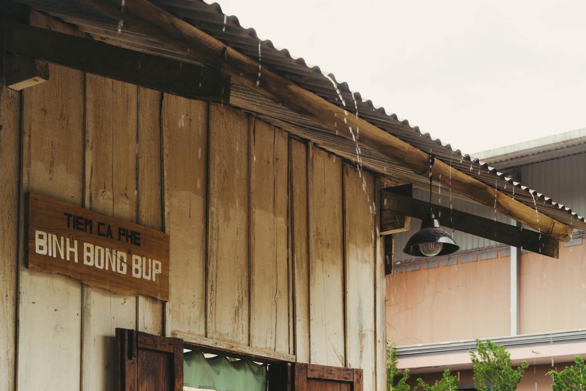 A rustic coffee shop roof dripping with rain, vintage sign visible.