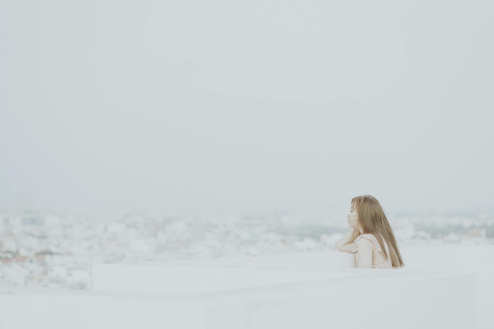 A woman with long hair gazes in a thoughtful mood on a foggy rooftop.