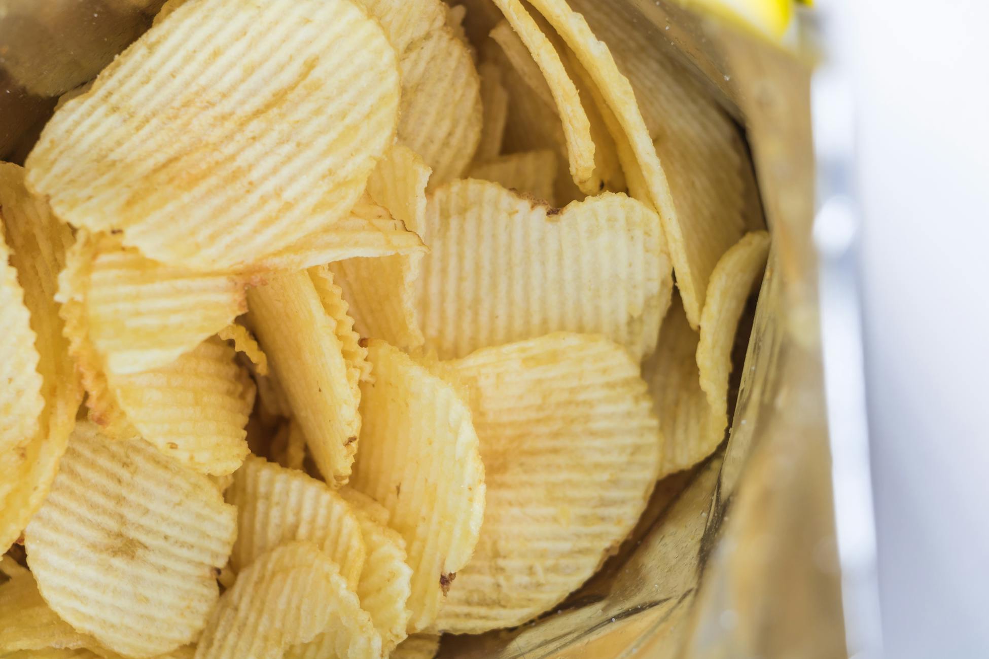 Close-up of ridged potato chips inside an opened snack bag, ready to eat.