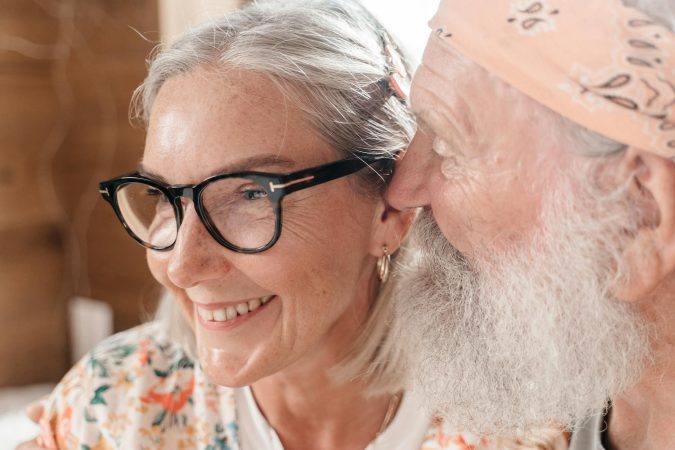 Elderly couple with eyeglasses sharing a joyful moment indoors, exuding love and happiness.