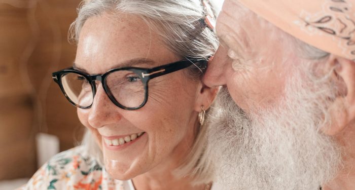 Elderly couple with eyeglasses sharing a joyful moment indoors, exuding love and happiness.