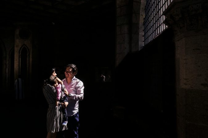 A joyful family moment captured in a dimly lit historic building with beautiful architecture.