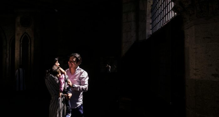 A joyful family moment captured in a dimly lit historic building with beautiful architecture.