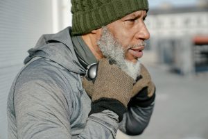 Side view of bearded elderly African American male in green knitted hat wit headphones on neck looking away