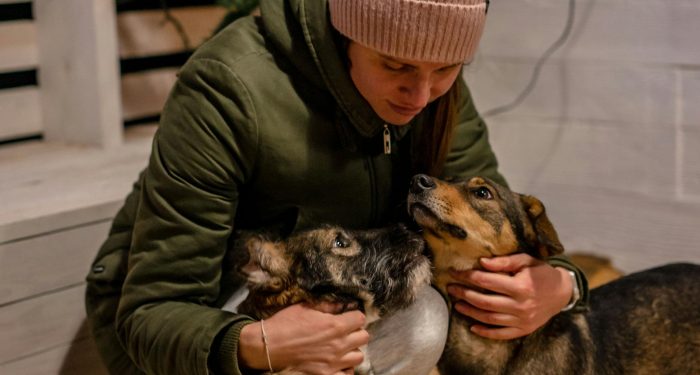 Warm winter snuggle with woman in beanie and her two cuddly dogs.