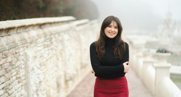 Portrait of a smiling woman in a red skirt and black sweater on a misty autumn day.