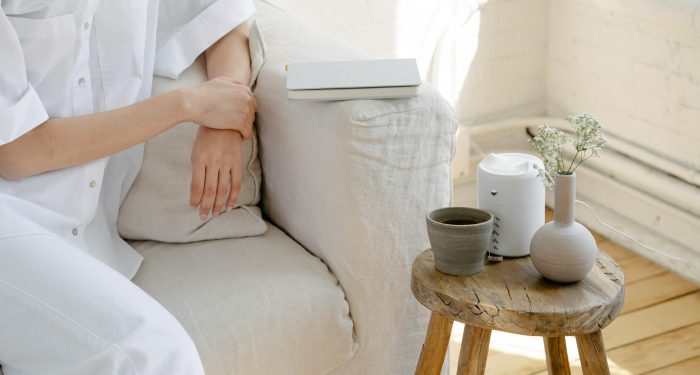 A serene indoor scene featuring a person relaxing with coffee near a minimalist vase on a stool.